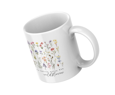 Weiße Keramiktasse mit zarten Wildblumen in Aquarelloptik und dem Zitat „You belong among the wildflowers“, schräg von oben fotografiert auf weißem Hintergrund.
